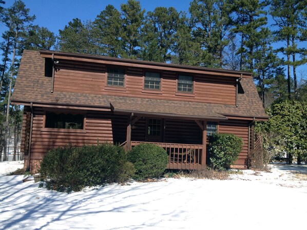 A two-story log cabin with a front porch and a covered entryway.