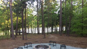 A fire pit area with benches and a gravel path in a forested setting.