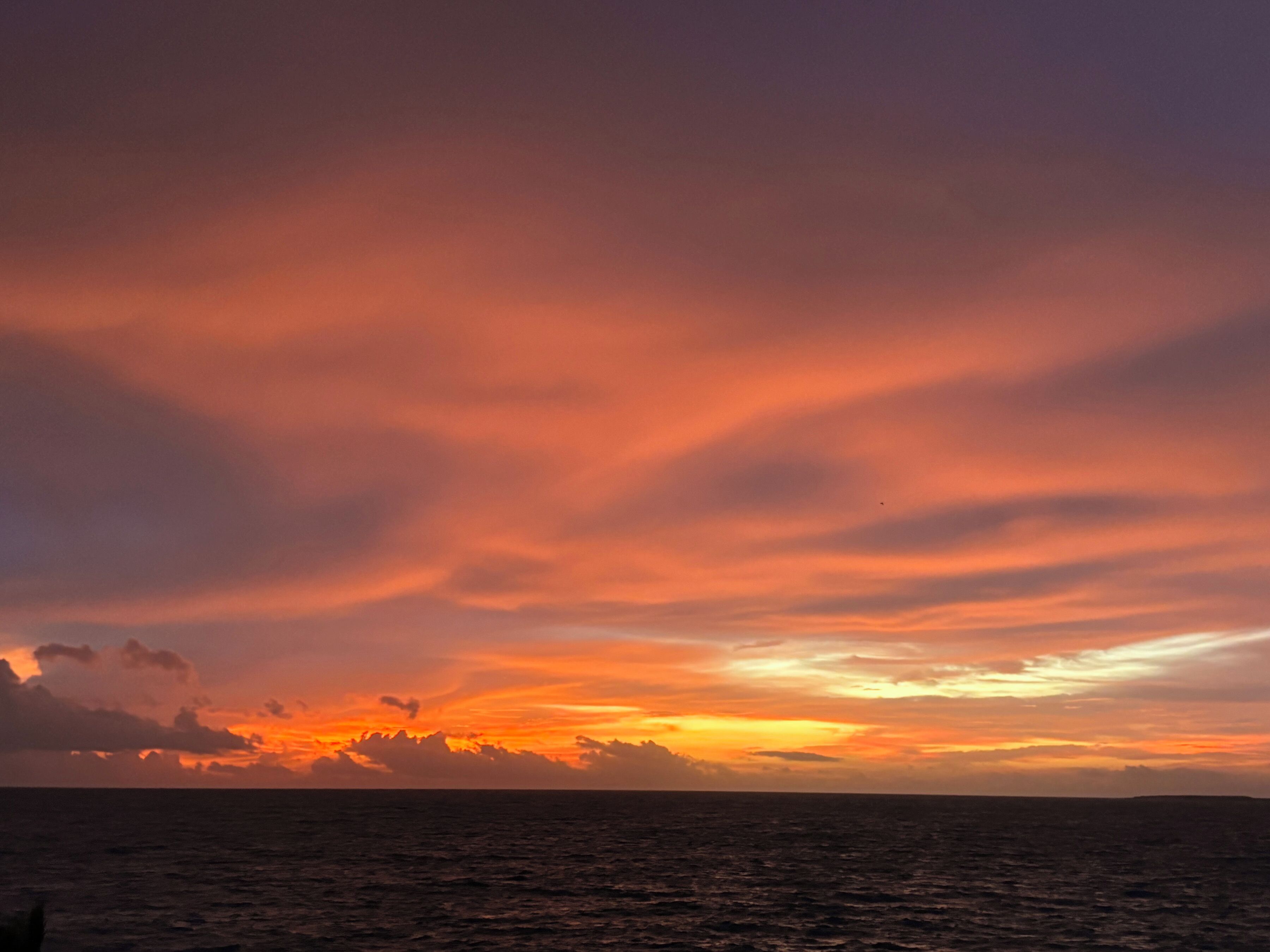 Un coucher de soleil sur l’océan, avec un horizon dégagé.