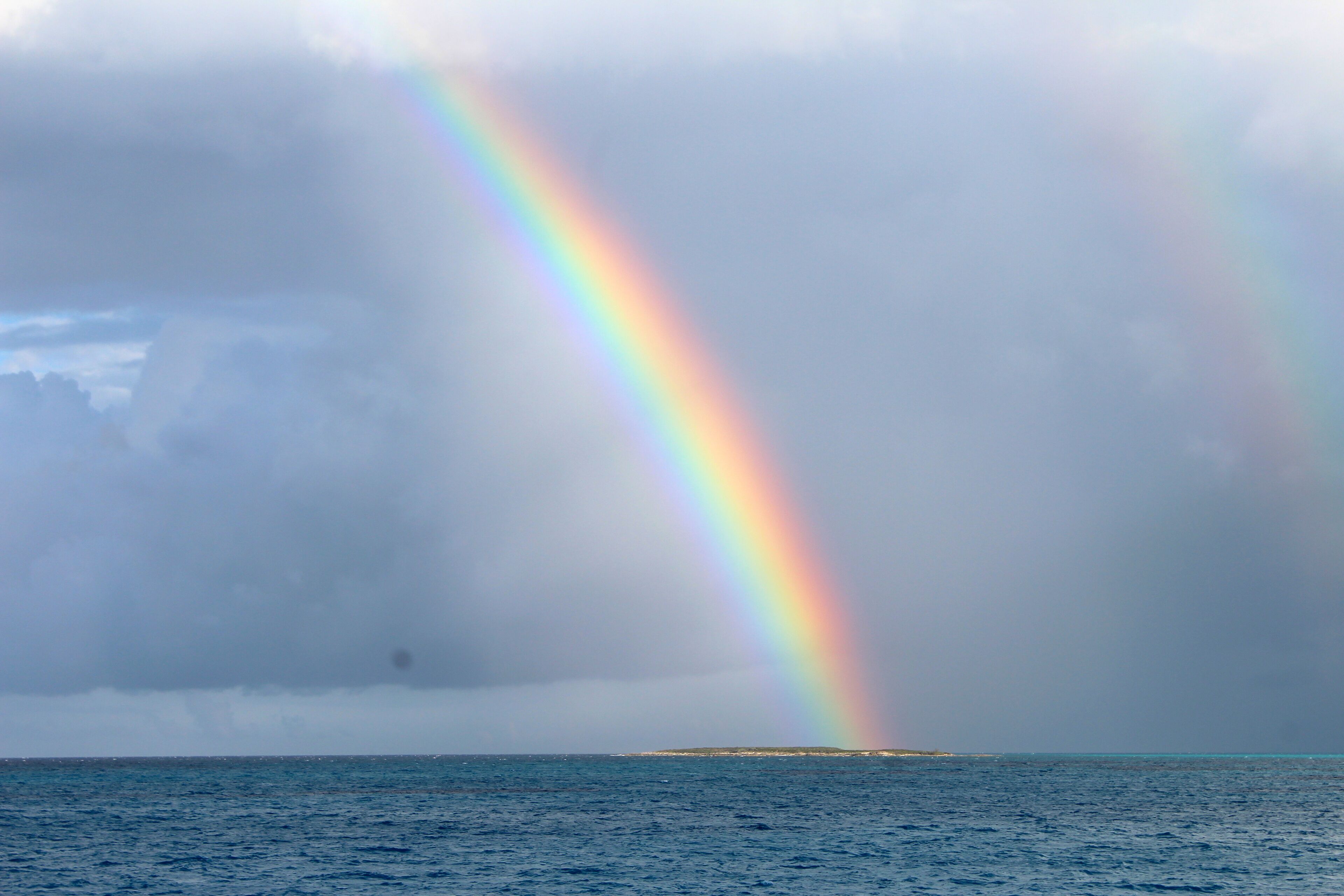 A rainbow over a body of water with a distant landmass.