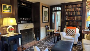 Un salon chaleureux avec une cheminée, une bibliothèque et un coin salon confortable.