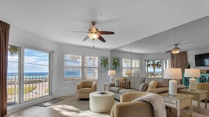 A spacious living room with a large window overlooking the ocean, a ceiling fan, and a television. - MARAVILLA LUXURIOUS GULF FRONT PET FRIENDLY CONDO NEWLY REMODELED (Destin)
