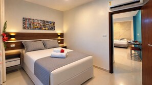 Una habitación de hotel con cama, mesita de noche, decoración en la pared y vista a la habitación contigua.