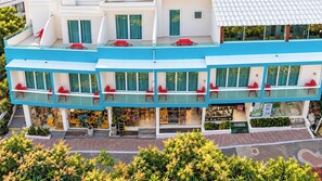 Un edificio de varios pisos con balcones, una tienda en la planta baja y un jardín.
