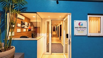 Et hotellets reception område med en skranke, en potteplante og et skilt der angiver navnet og typen af overnatningsstedet.