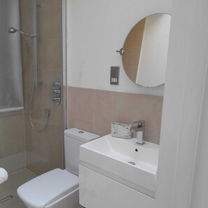 Ein Badezimmer mit Toilette, Waschbecken, Spiegel und Dusche.