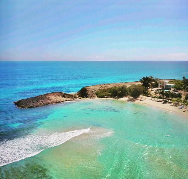 A coastal property with a beach, clear waters, and a structure with a roof. - Casa Playa Ramey Studio (Aguadilla)