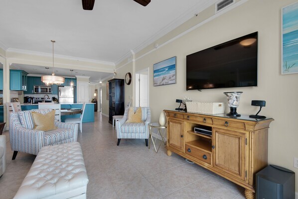 A spacious living room with a large white sofa, a wooden cabinet, and a television on the wall. - Beach Gulf View Condo, Dog OK, WiFi, Self Check In-Out, High cleanliness Stdrs. (Miramar Beach)