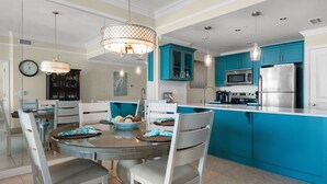 A modern kitchen with teal cabinetry, stainless steel appliances, and a round dining table with chairs. - Beach Gulf View Condo, Dog OK, WiFi, Self Check In-Out, High cleanliness Stdrs. (Miramar Beach)