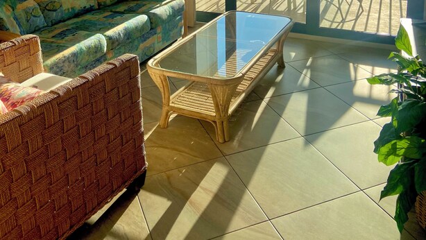 A balcony with a glass table and chairs, a sofa, and a painting on the wall. - Seawinds  Beautiful Beachfront Renovated Condo. Watch the dolphins go by! (Marco Island)