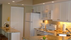 A kitchen with white cabinets, a refrigerator, a microwave, a stove, and a sink. - Seawinds  Beautiful Beachfront Renovated Condo. Watch the dolphins go by! (Marco Island)