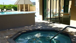 A swimming pool with a hot tub, lounge chairs, and a covered seating area. - Seawinds  Beautiful Beachfront Renovated Condo. Watch the dolphins go by! (Marco Island)