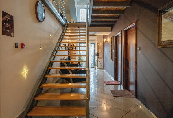 A staircase with wooden steps and metal railings, leading to a landing with a view of the outdoors. - Hotel Atrium (Niksic)