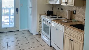 Een keuken met beige kastjes, een witte kookplaat, een magnetron en een vaatwasser.