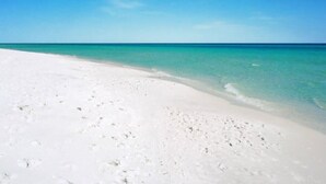Une plage de sable blanc bordée d’une eau turquoise cristalline.