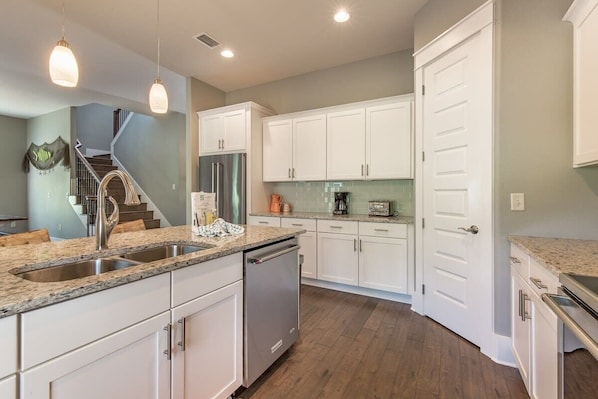 A modern kitchen with white cabinets, granite countertops, stainless steel appliances, and pendant lighting. - Huge (~2,700 SqFt) Home! Golf Cart, 6 Bikes! Beach & Pool Nearby! ~ Shore Thing at Frangista Beach (Miramar Beach)