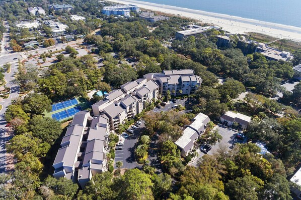 An aerial view of a residential area with multiple buildings, a beach, and a tennis court. - 2BR 2BA New King Mattress, Walk-In Shower, Pool, Balcony, Tennis, Pickleball (Hilton Head Island)