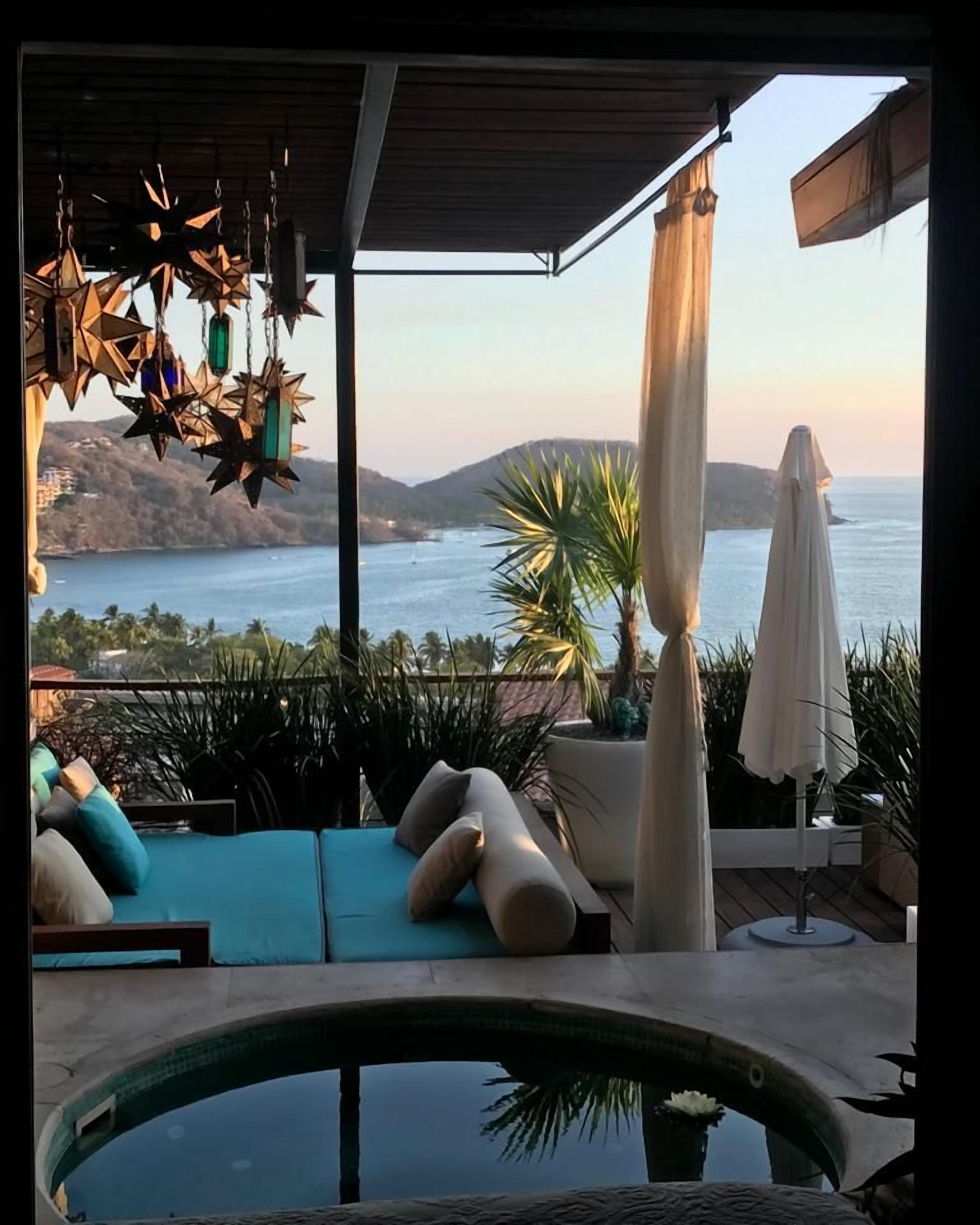 Un espace aménagé au bord de la piscine, avec vue sur la mer, des chaises longues et des guirlandes lumineuses décoratives.
