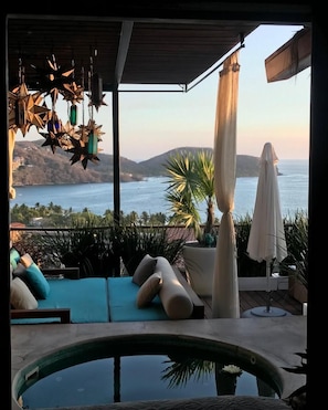 A poolside area with a view of the sea, lounge chairs, and decorative hanging lights.