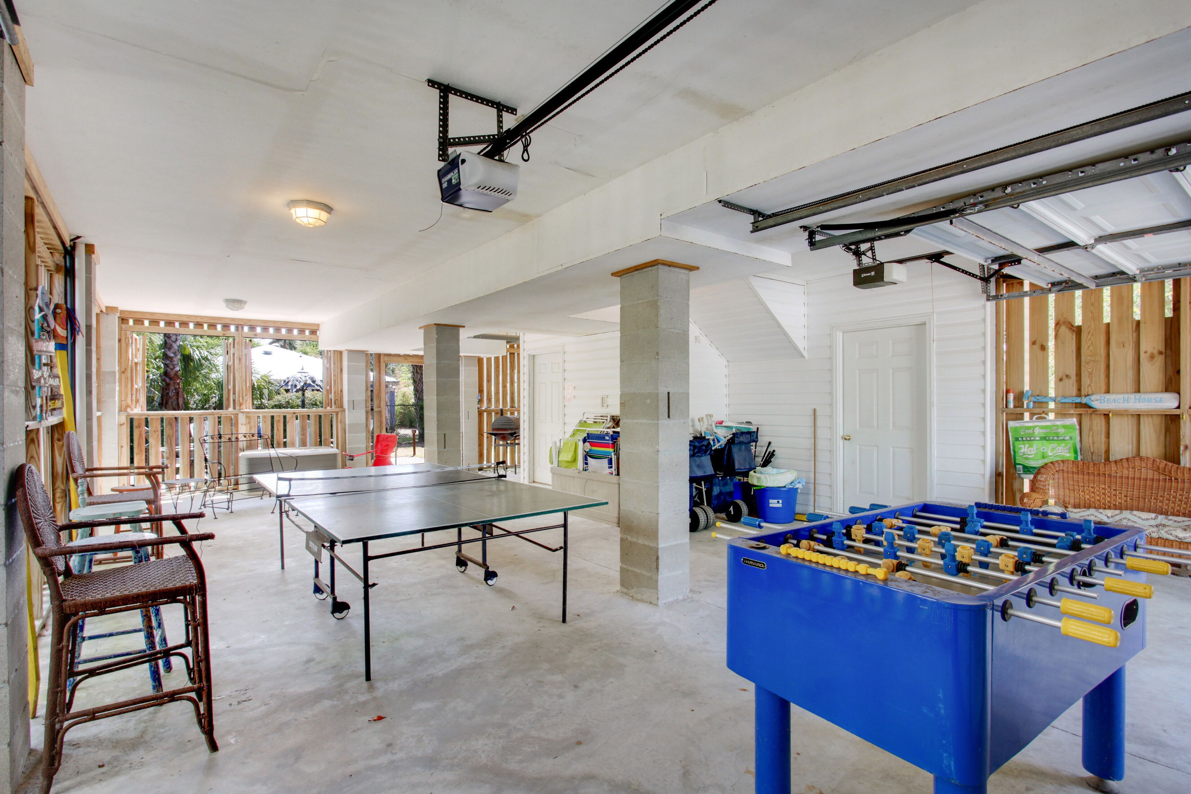 A spacious room with a ping pong table, a foosball table, and a dining area with chairs and a table.