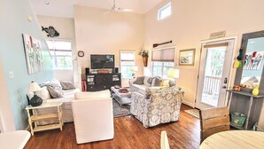 A spacious living room with a fireplace, a television, and a dining area with a table and chairs. - Peaceful House on South Island with Bikes- discounts on weekly summer stays! (Tybee Island)