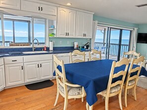 A kitchen with a view of the ocean, a dining table with chairs, and a sign that reads 'WELCOME ABOARD'. - Optimystical Vista — Gulf-Front Escape with 270° Views & Elevator (Spring Hill)