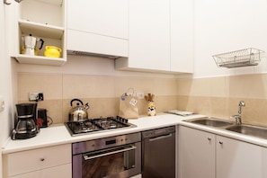 Una cocina moderna con estufa a gas, horno, lavavajillas y un fregadero.