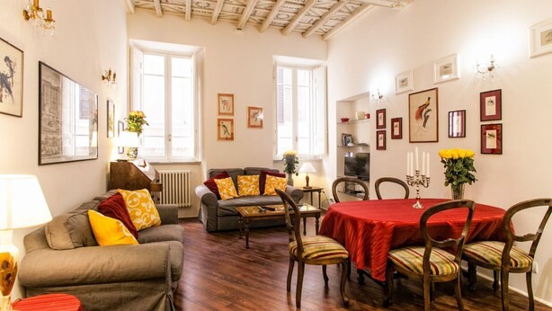 Een gezellige woonkamer met een bank, een eettafel met stoelen en een open haard.