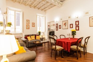 Una sala de estar amplia con sofá, mesa de comedor y sillas, y una televisión.