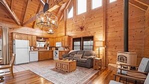A wooden cabin interior with a kitchen, living area, and a fireplace. - Quiet Cabin Nestled in trees with King -hot tub, pool, pool table, fishing pond (Sevierville)