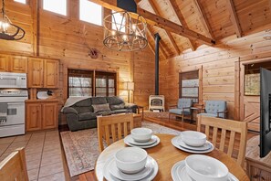 Cozy cabin interior with a dining area, comfortable sofa, and fireplace.