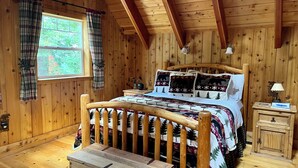 A wooden cabin bedroom with a bed, nightstand, and chest of drawers.