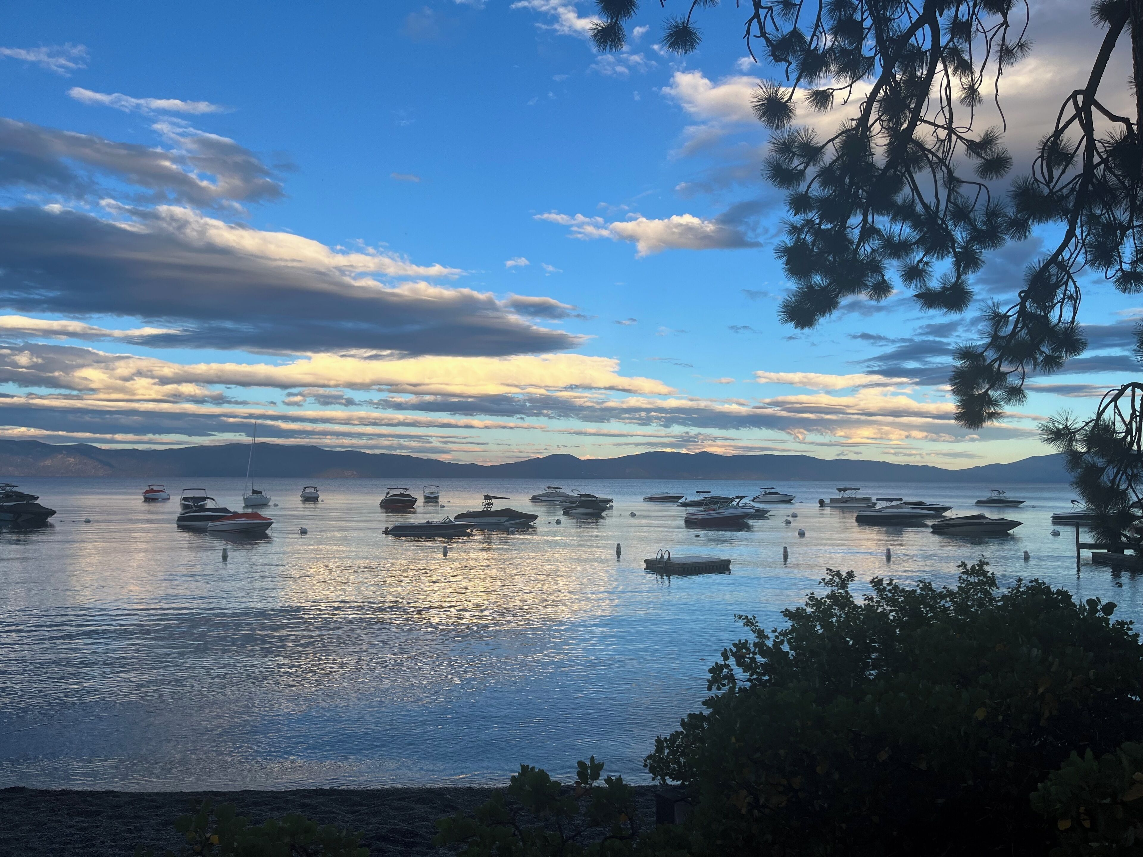 A calm lake with boats and mountains in the background.