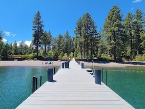Une jetée en bois s’étendant dans un lac aux eaux limpides, entourée d’une forêt dense.