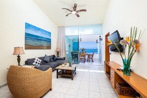 Relax in this stylish living room with a sofa, coffee table, and wall-mounted TV, offering a view of the sea.
