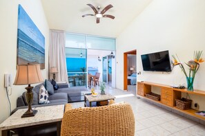 Enjoy the stunning sea view from this spacious living room with a sofa, coffee table, and wall-mounted TV.