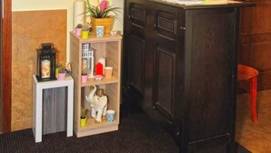 A reception area with a wooden desk, a clock, a mirror, and a small shelf with decorative items.