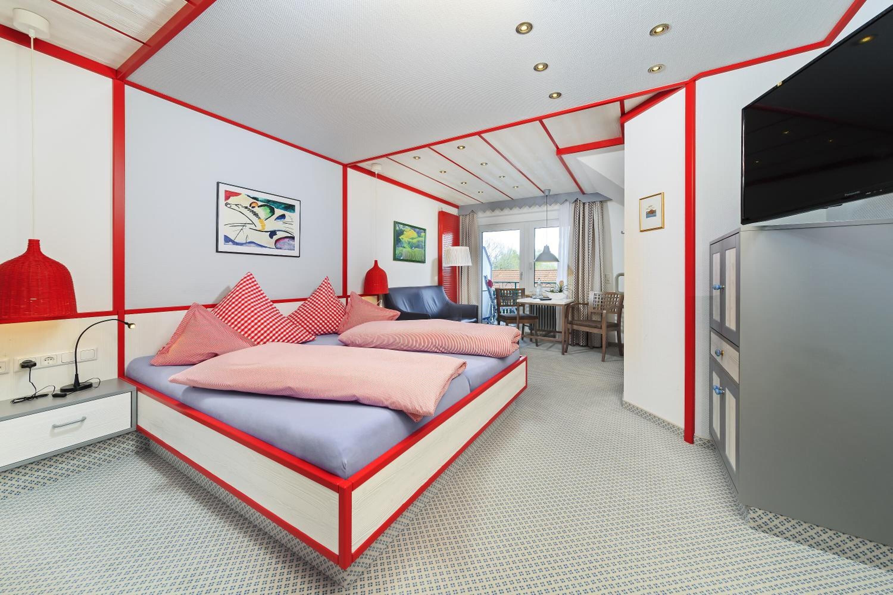 Un dormitorio con cama, mesita de noche, lámpara y vistas al comedor.
