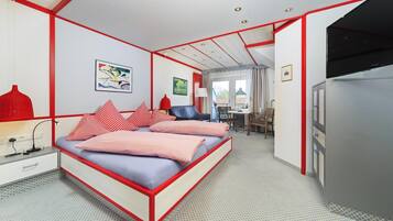 Un dormitorio con cama, mesita de noche, lámpara y vistas al comedor.