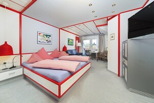 Un dormitorio con cama, mesita de noche, lámpara y vistas al comedor.