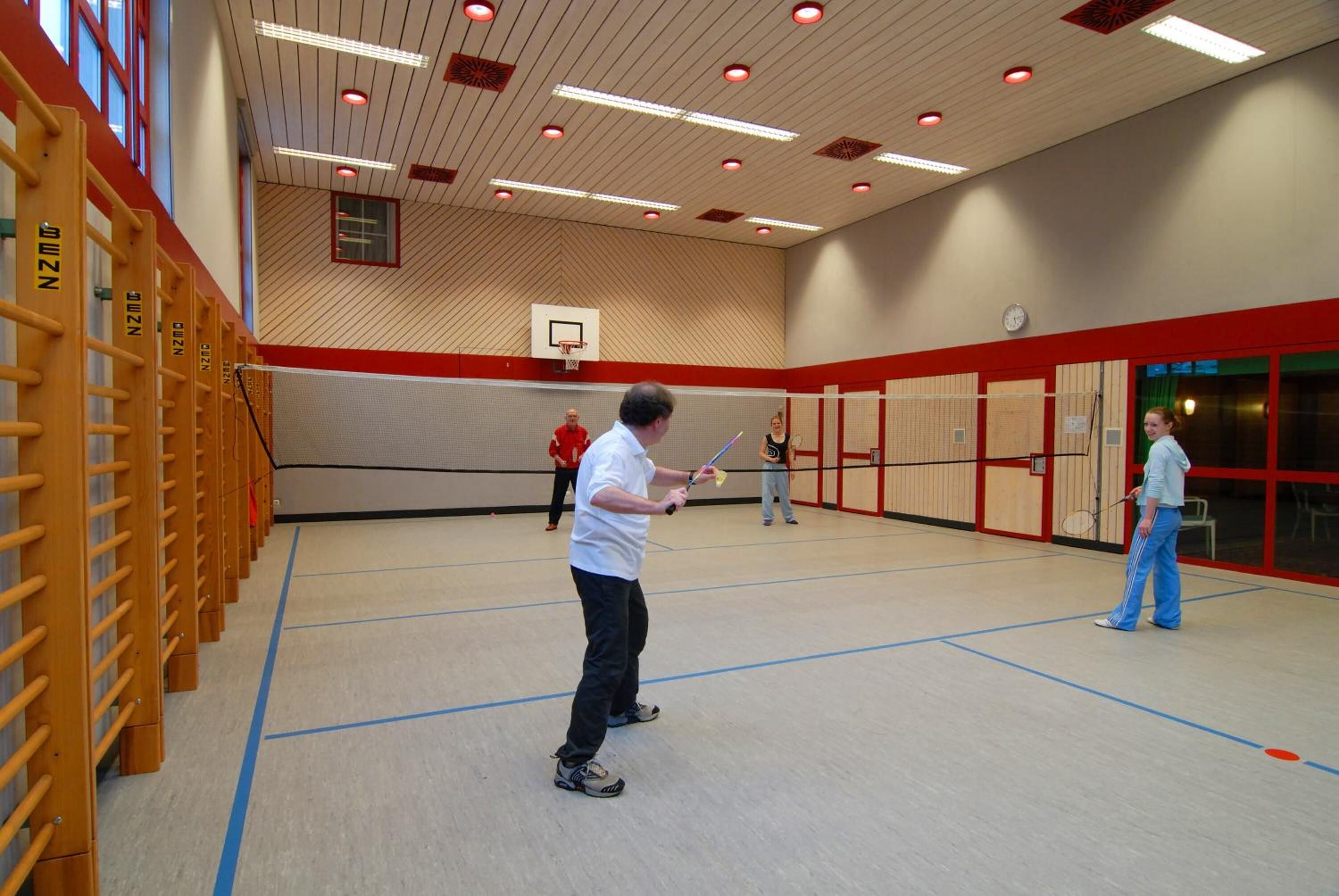 Un gimnasio con una cancha de baloncesto, estructuras de escalada de madera y un aro de baloncesto.