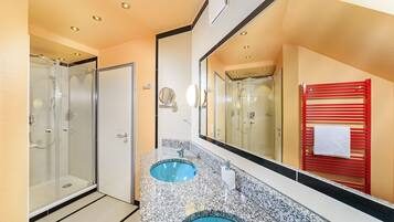 A modern bathroom with two sinks, a glass shower enclosure, and a large mirror.