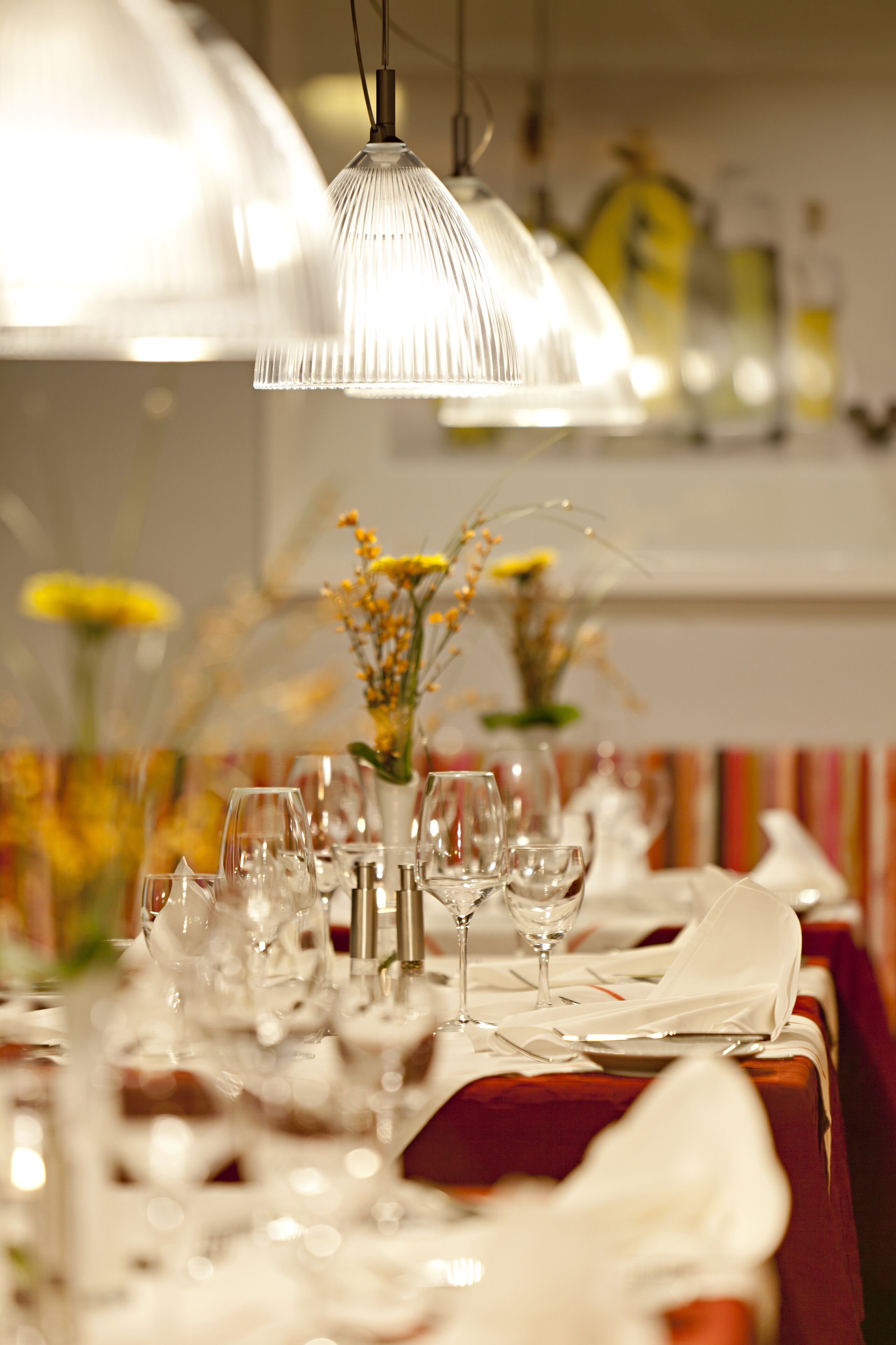 A dining table set with multiple wine glasses and a vase of flowers.