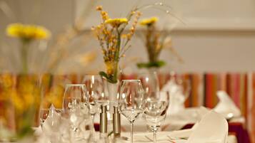A dining table set with multiple wine glasses and a vase of flowers.