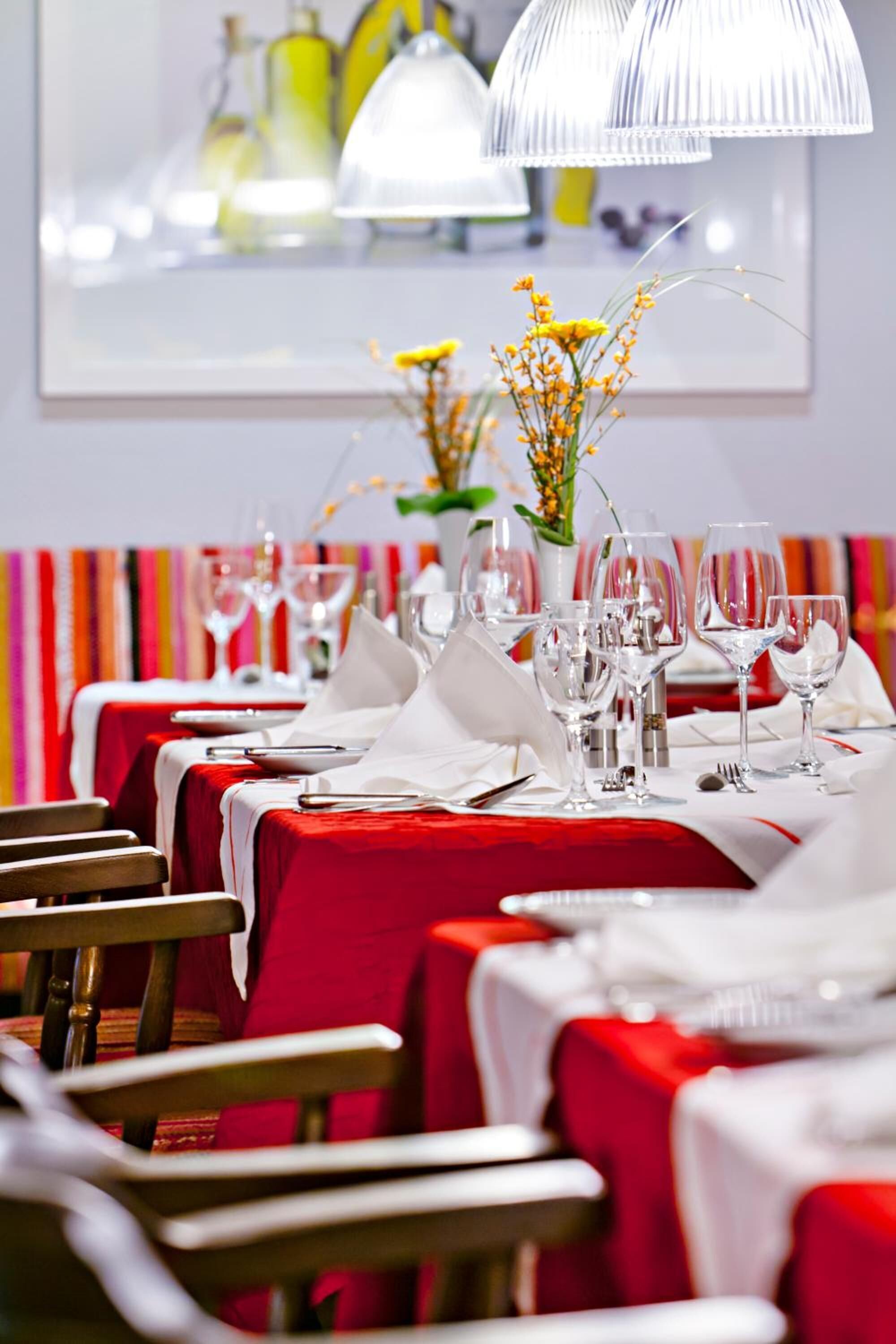 A restaurant with red tablecloths, white napkins, and clear glassware.