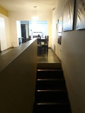 A long, narrow hallway with a staircase leading to a dining area. - Como en Casa Hostel (Posadas)