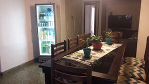 Un espace repas comprenant une table, des chaises, un réfrigérateur et un téléviseur.