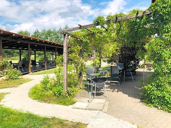 Un patio al aire libre con pérgola, mobiliario y un sendero.