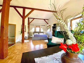 Amplia sala de estar con piso de madera, un sofá, una mesita de centro y un florero con flores.