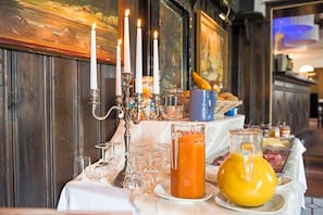 A breakfast buffet with a variety of food items, a candelabra with lit candles, and a glass pitcher of orange juice. - Weivue Mv Hle (Breitenworbis)